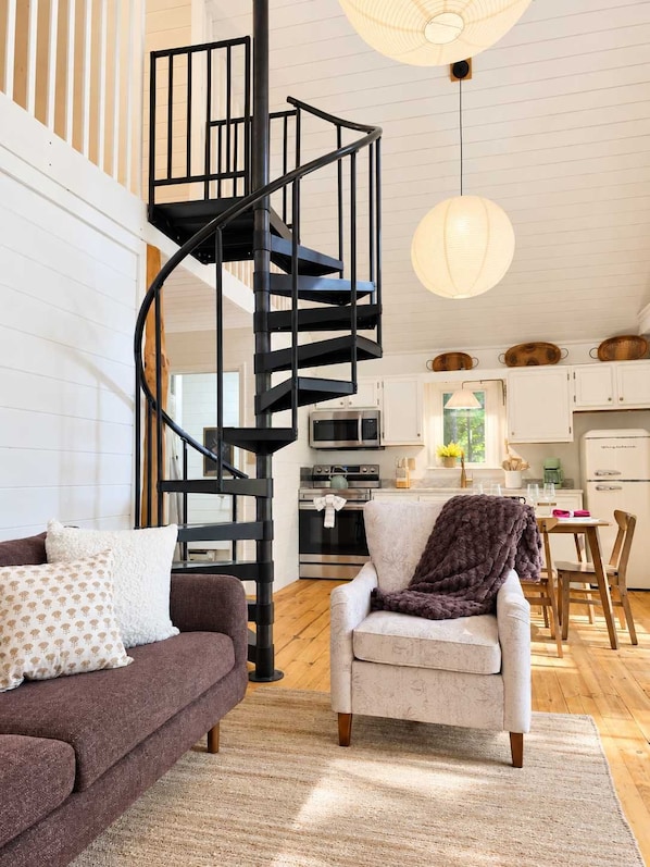 Un interior moderno con una escalera en espiral, una zona de comedor y una cocina.