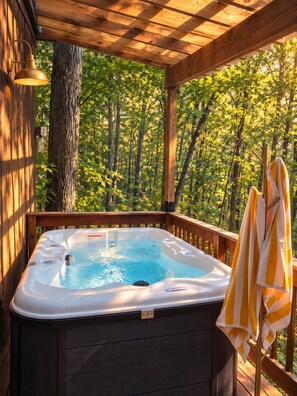 Un jacuzzi en una terraza de madera con vista a un bosque.