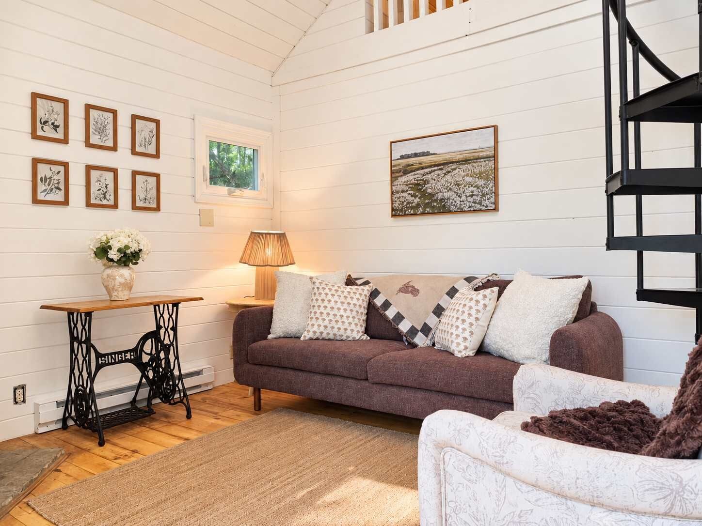 A cozy living room with a brown sofa, a patterned throw, and a lamp.