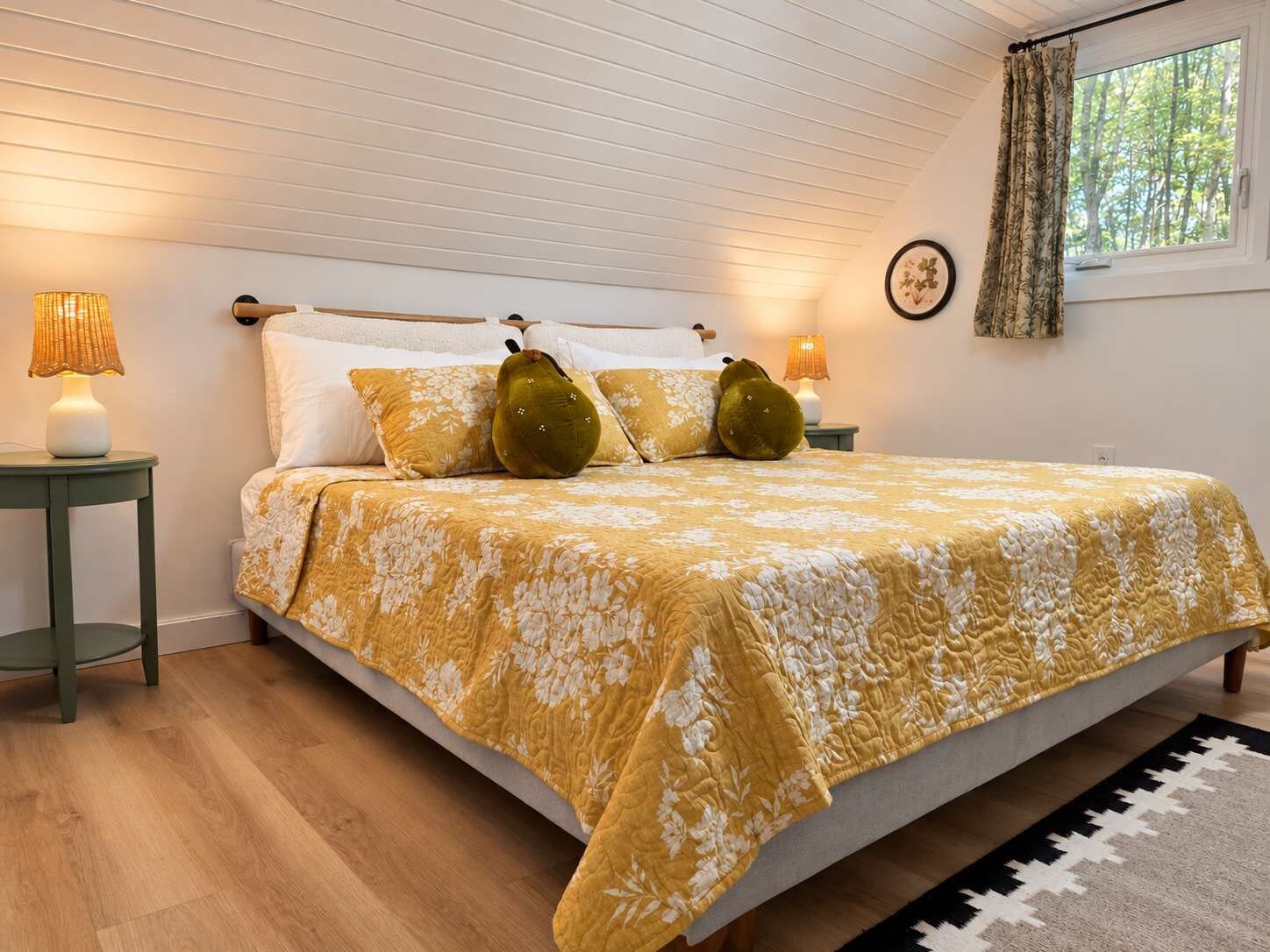 Un dormitorio con una cama, dos mesitas de noche, una ventana con cortinas y un reloj de pared.