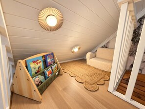 Een gezellig zolderkamer met een schuine kap, een houten boekenkast, een zachte bank en een geweven vloerkleed.