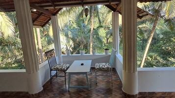 Un espacio de estar al aire libre cubierto con una mesa y dos sillas, rodeado de exuberante vegetación tropical.