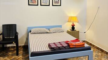 A bedroom with a bed, a chair, a nightstand, and a lamp.