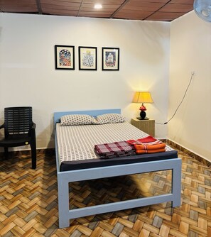 Quarto com cama, poltrona, mesa de cabeceira e abajur.