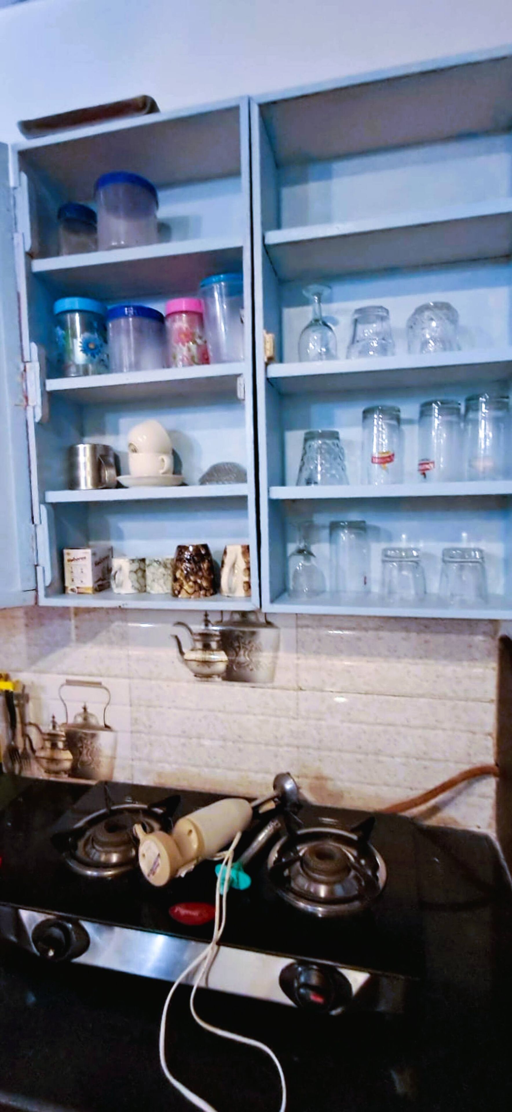Una cucina con un fornello, pensili e una varietà di utensili da cucina.