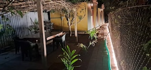 Uma área de refeições ao ar livre com mesas, cadeiras, um telhado de palha e uma cerca.