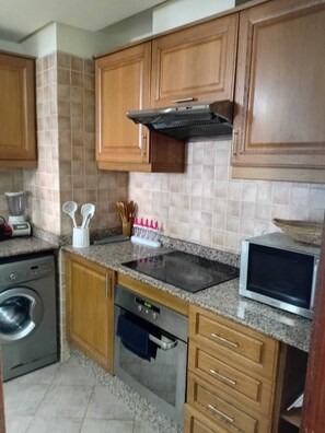 A kitchen with wooden cabinets, a built-in oven, a microwave, and a blender. - Comfortable , quiet , and beautiful apartment. (Agadir)