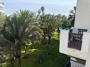 A courtyard with palm trees and a white building with a balcony. - Comfortable , quiet , and beautiful apartment. (Agadir)