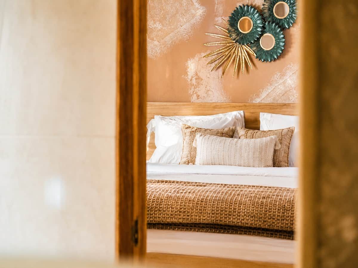 A bedroom with a bed, pillows, a woven blanket, and a wall decoration.