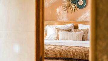 A bedroom with a bed, pillows, a woven blanket, and a wall decoration.