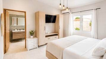 Un dormitorio con cama, televisor, armario y ventana con cortinas.
