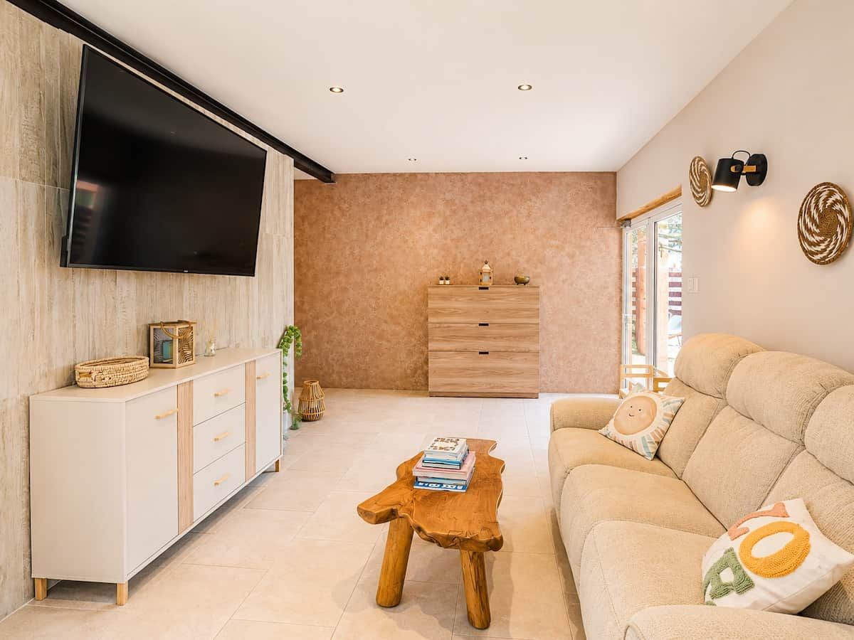 Una sala de estar moderna con un televisor de pantalla plana, una mesa de centro de madera, un sofá color beige y un mueble minimalista.