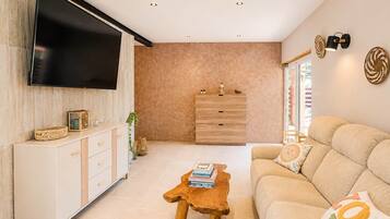 Una sala de estar moderna con un televisor de pantalla plana, una mesa de centro de madera, un sofá color beige y un mueble minimalista.