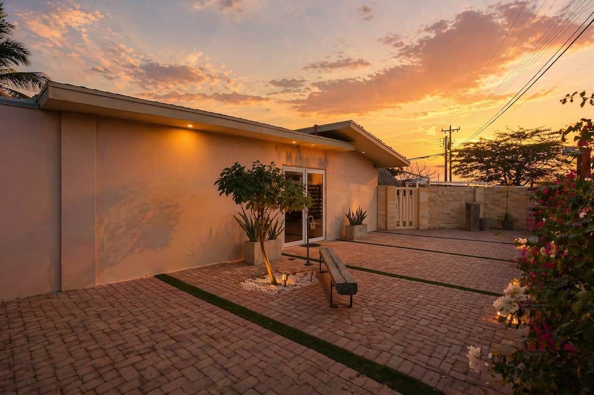 Un edificio residencial con un patio empedrado, un banco y plantas en macetas.