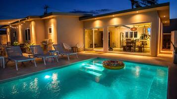 A swimming pool with lounge chairs and a dining area.