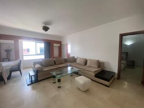 A living room with a sofa, glass coffee table, and a small table with chairs. - Stylish Marina Apartment Steps from Beach (Agadir)
