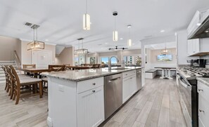 A modern kitchen with a central island, white cabinetry, and pendant lighting. - Lux Beach Getaway | Sleeps 28 | Beach Steps Away (Gulf Shores)
