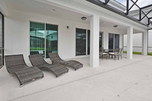 Un espace extérieur abrité, aménagé avec des fauteuils et une table.