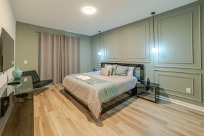 Un dormitorio con cama, mesitas de noche, un espejo y una cortina.