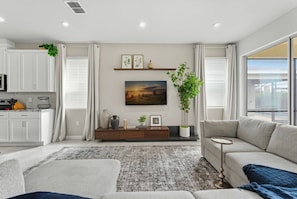 Ein modernes Wohnzimmer mit Sofa, Couchtisch, Kamin und Küchenbereich mit Schränken und Mikrowelle.