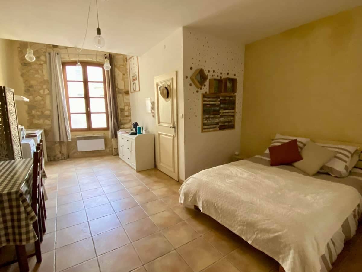 A bedroom with a bed, a dresser, a desk, and a window.