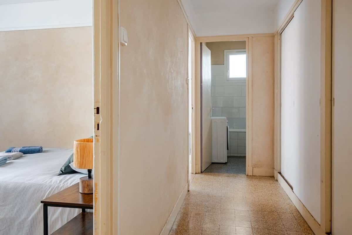 A narrow hallway leading to a bathroom with a toilet and a shower.