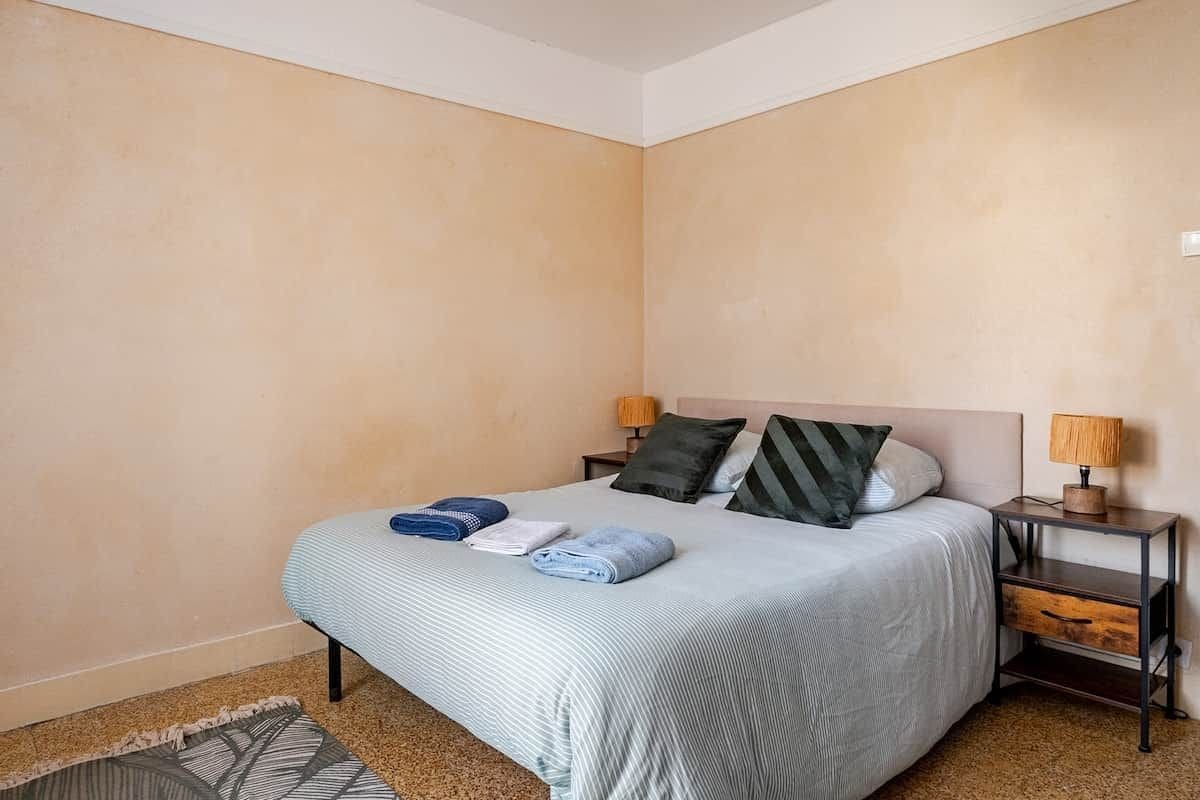 A bedroom with a bed, two bedside tables, and a nightstand.