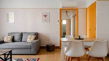 Una sala de estar moderna con un sofá gris, sillas blancas, una mesita y un tapete colorido.
