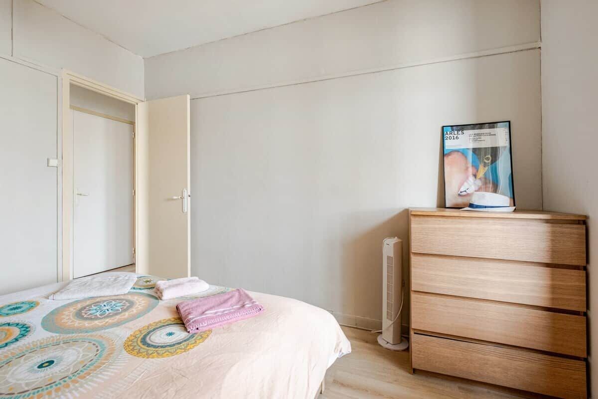 A bedroom with a bed, a dresser, and a poster on the wall.