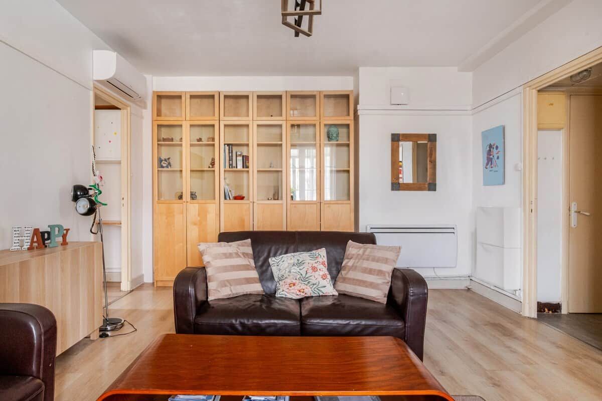 Een woonkamer met een leren bank, een houten kast en een salontafel.