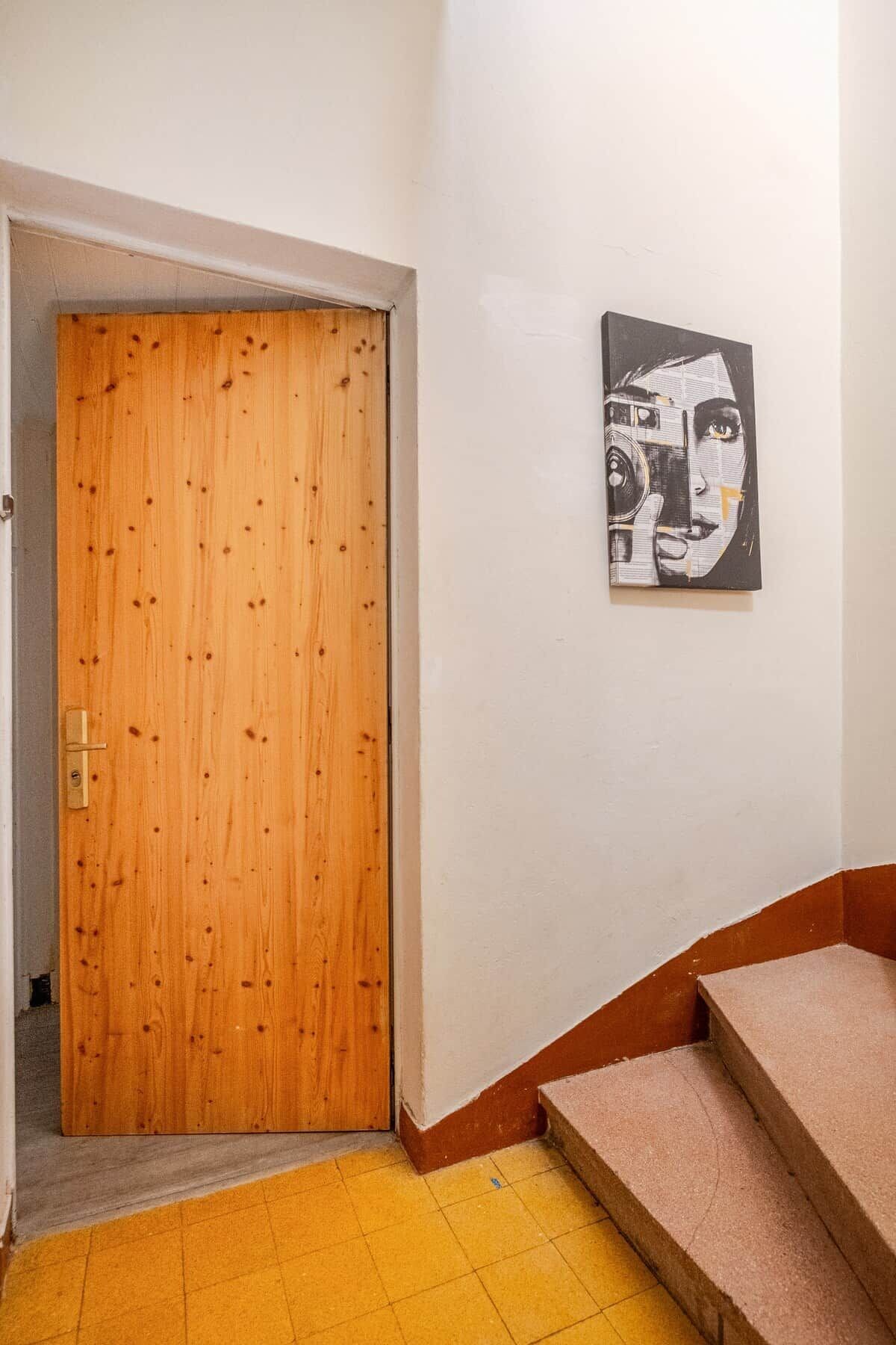 Una puerta de madera, una escalera y una obra de arte colgada en la pared.