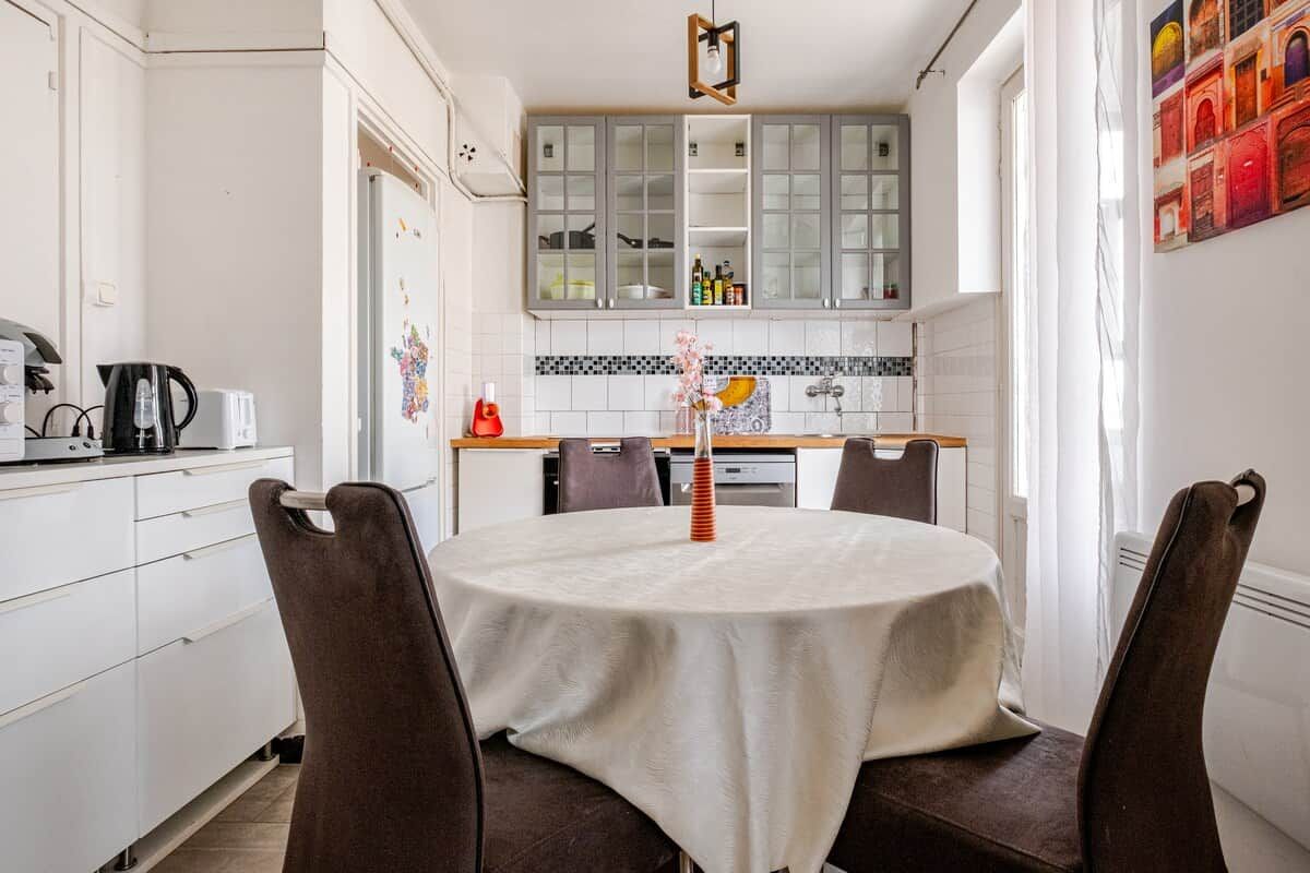 Un comedor con una mesa redonda, sillas y una cocina al fondo.