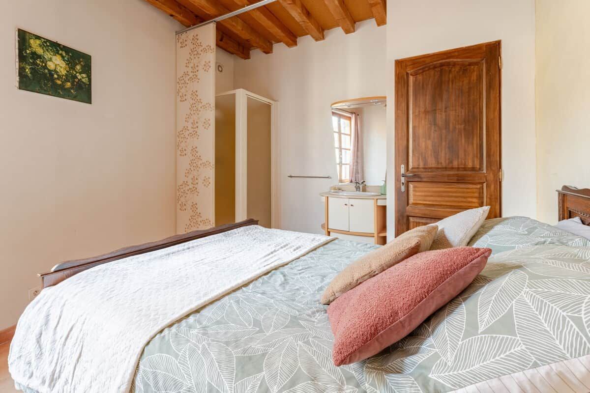 A bedroom with a bed, a wooden door, a dresser, and a mirror.