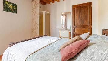 A bedroom with a bed, a wooden door, a dresser, and a mirror.