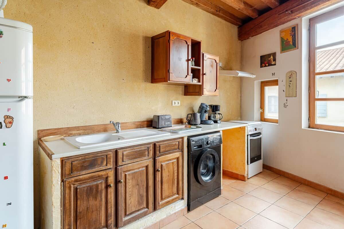 A kitchen with wooden cabinets, a washing machine, a stove, and a sink.