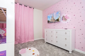 Ein Zimmer mit einer rosafarbenen Wand, einem weißen Schminktisch mit Schubladen, einem rosa Vorhang und einem Bild von einem Schloss.