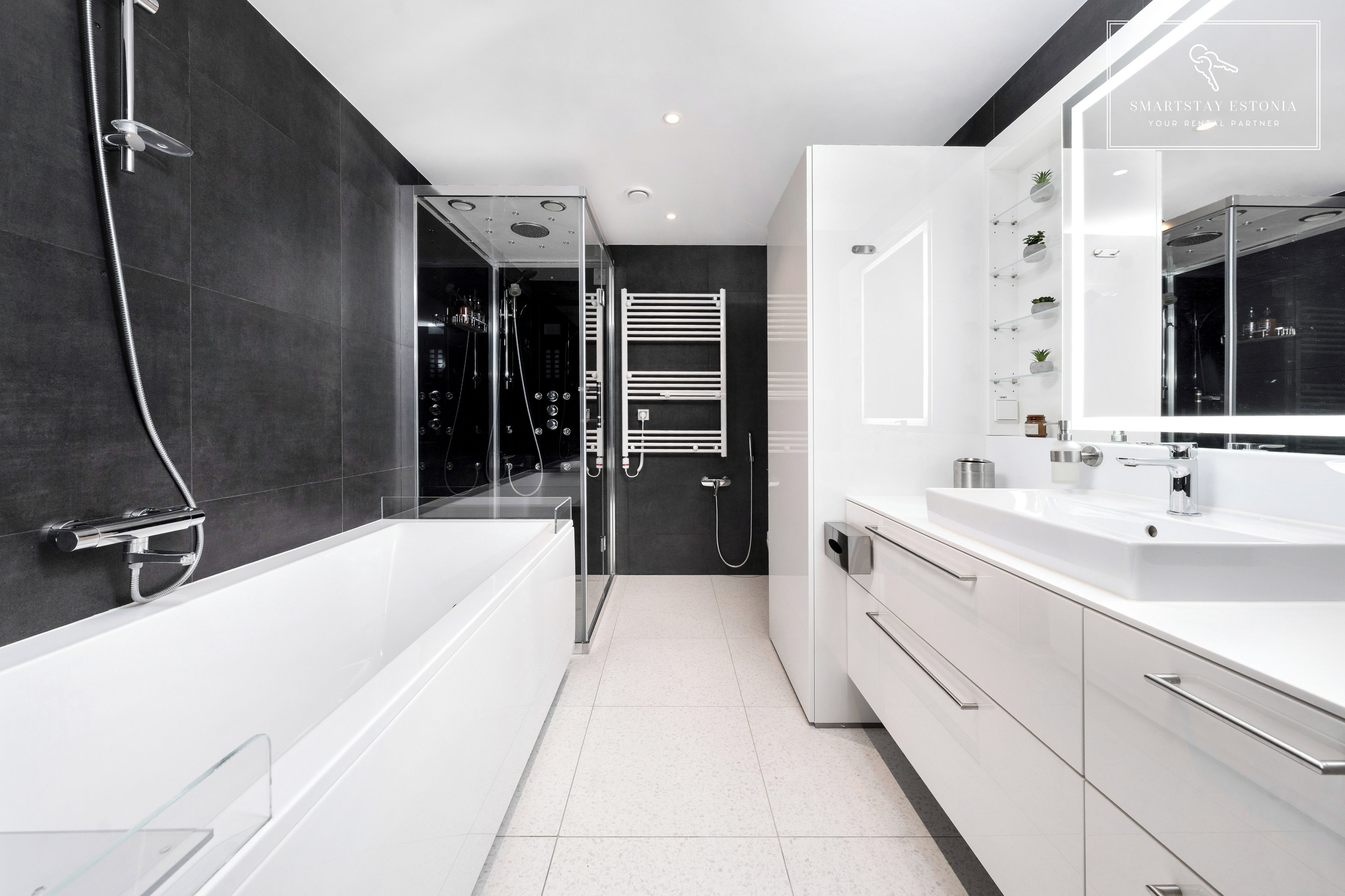 Et moderne badeværelse med brusebad, et stort spejl og et hvidt toiletbord med vask.
