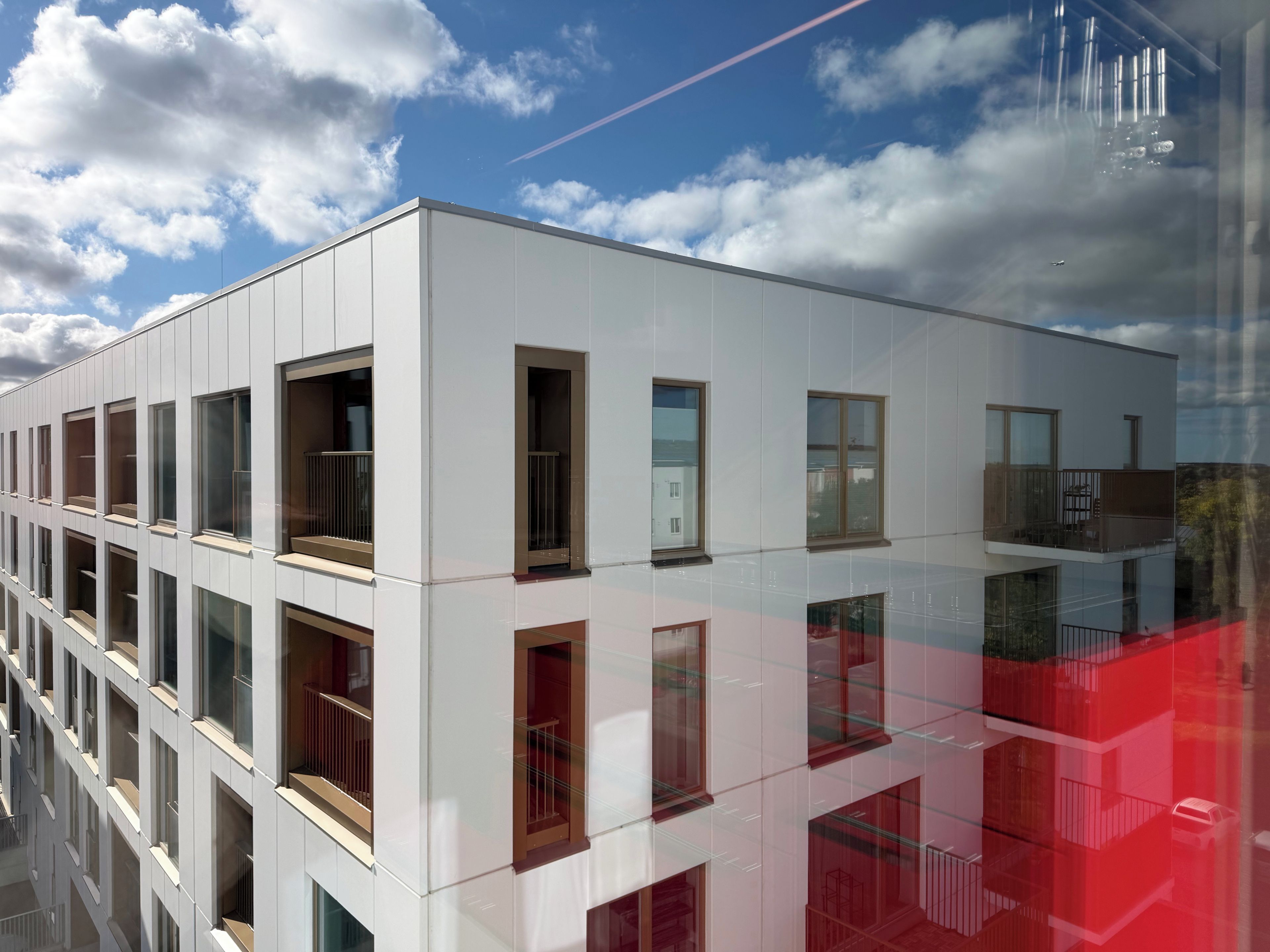A modern building with multiple floors, large windows, and balconies.