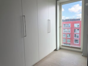 Una habitación con armarios blancos y un ventanal amplio.