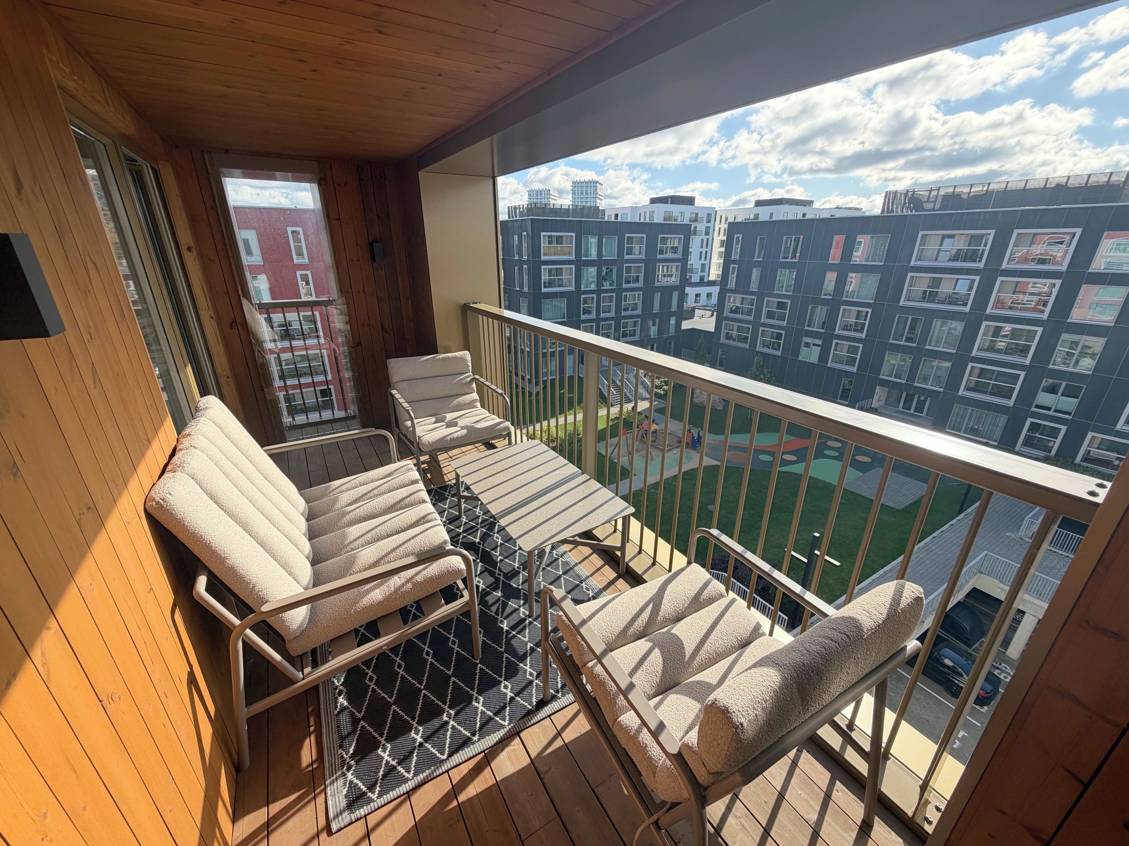 A balcony with a view of a cityscape, furnished with two chairs and a table.