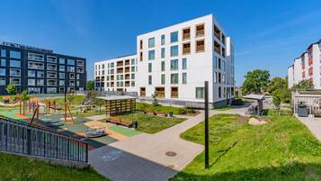 Un moderno edificio de apartamentos con parque infantil, zonas verdes y cielo despejado.
