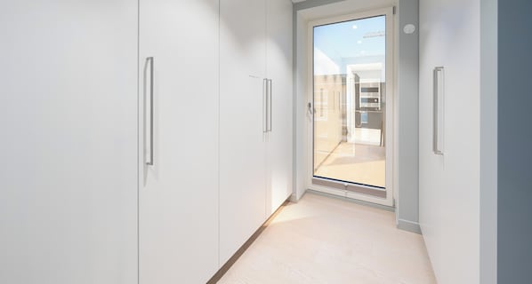 A narrow hallway with white cabinets and a sliding glass door leading to an outdoor area.