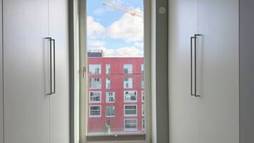 Un pasillo estrecho con una puerta que da a una ventana con vista a un edificio rojo y una grúa a lo lejos.