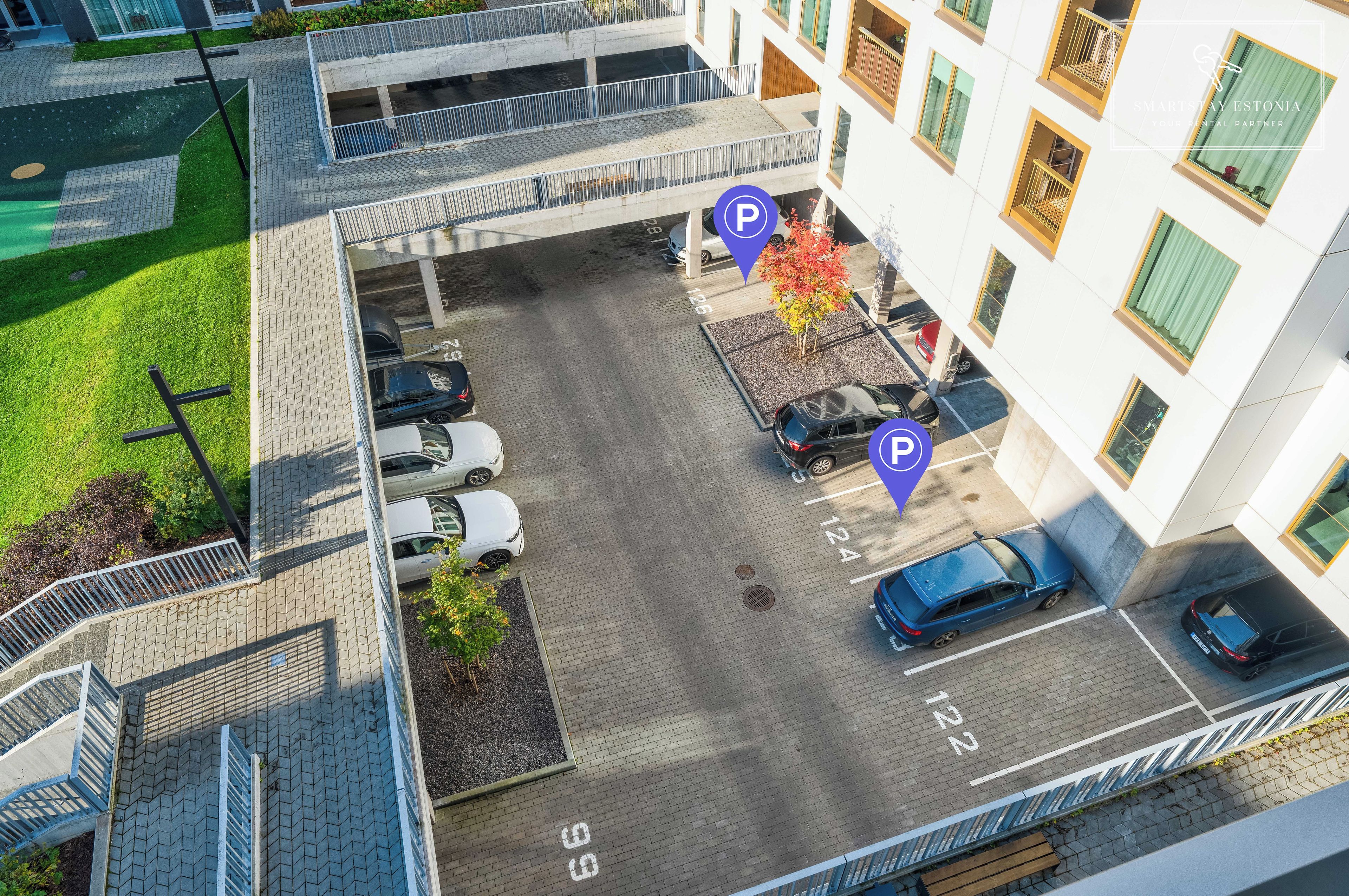 Luchtbeeld van een parkeerplaats met aangegeven parkeerplaatsen en een voetpad.