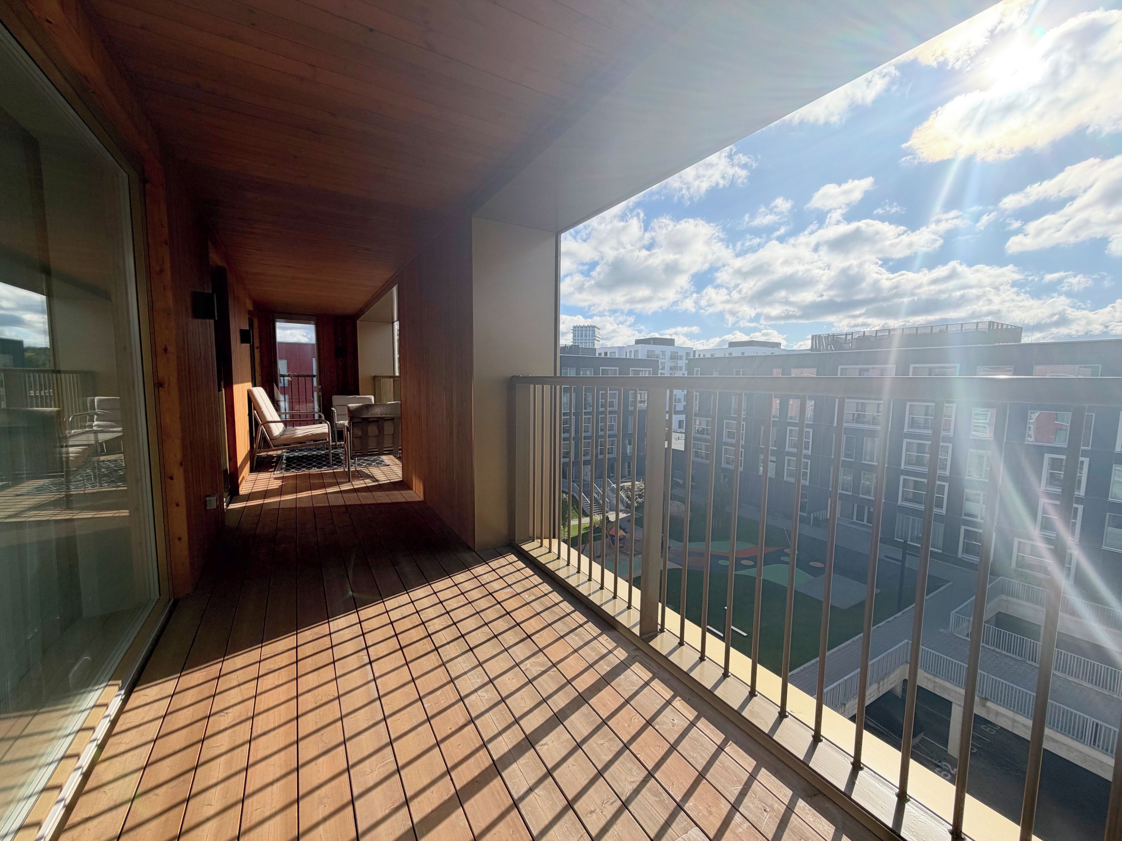 Un balcon doté d’un plancher en bois et offrant une vue sur le paysage urbain.