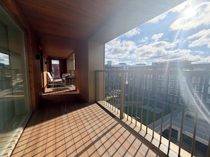 Un balcón con piso de madera y vista a un paisaje urbano.