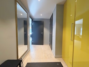 A hallway with a mirror, a bench, and a yellow door.