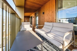 A modern interior with a wooden ceiling, a sofa, a table, and large windows.