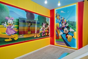 Ein helles Kinderzimmer mit Zeichentrickfiguren an den Wänden.