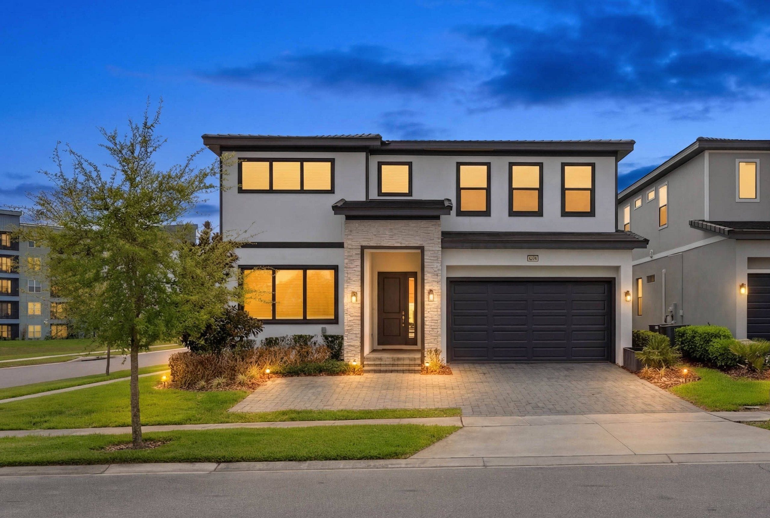 A modern two-story house with a garage, a well-maintained lawn, and a driveway leading to the entrance.